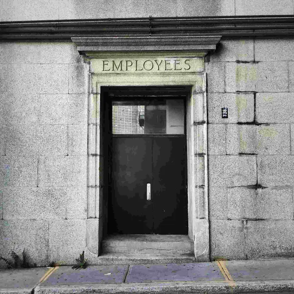 Stone building entrance with the word Employees carved above a dark door, illustrating growth without added headcount.