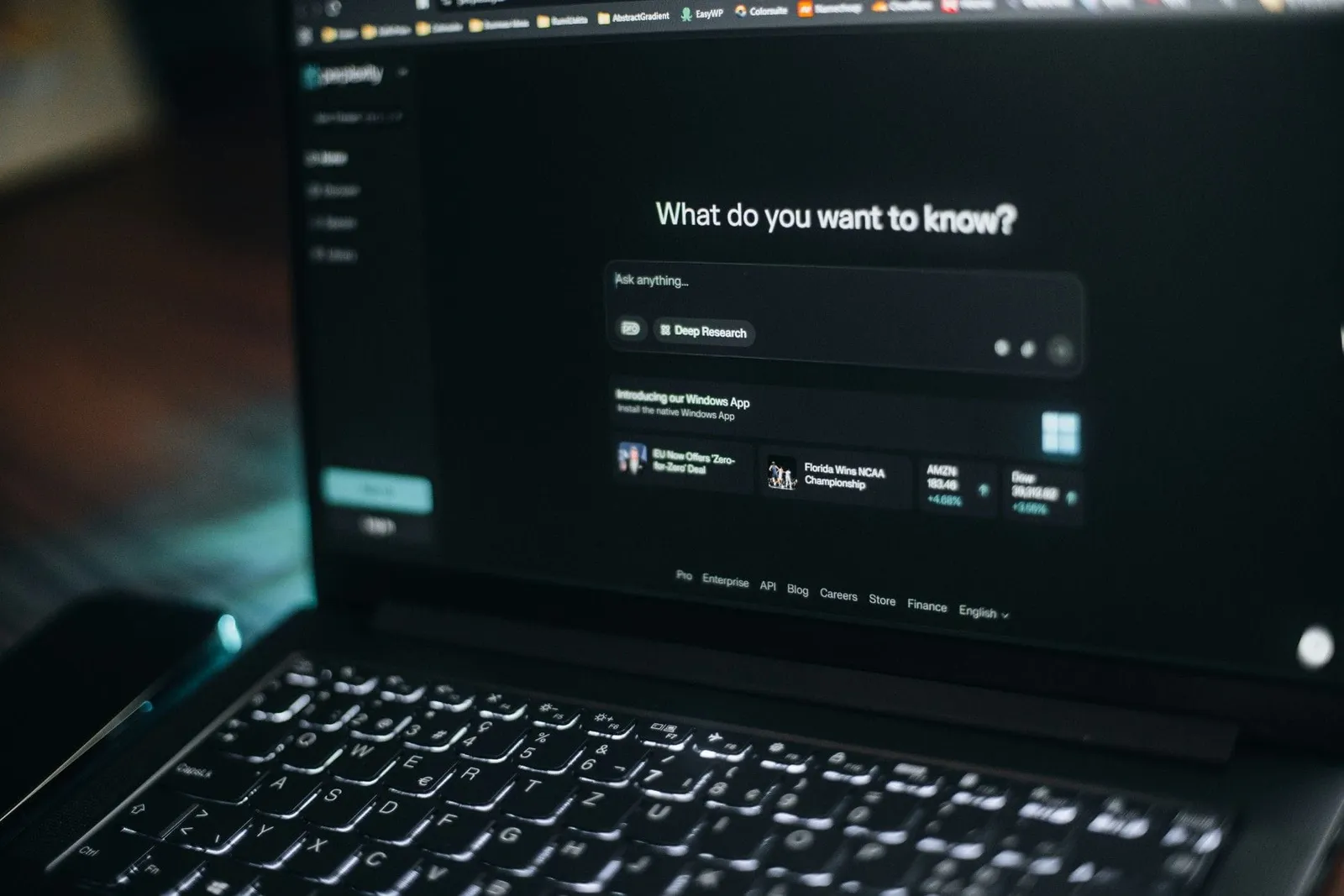 Laptop screen showing an AI assistant search prompt asking what do you want to know
